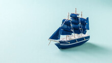 A Small Toy Sailboat On A Light Blue Background.