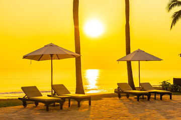 Wall Mural - Umbrella and chair around outdoor swimming pool with sea beach ocean at sunset