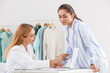 © Pixel-Shot - Female fashion designer and assistant working in studio