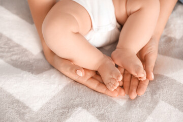 Canvas Print - Mother holding feet of her little baby on bed