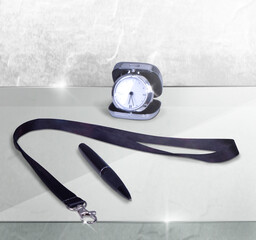 Wall Mural - Composition of promo products Black Lanyard Neck Strap with Metal Lobster Clip and black pen, silver table office clock. On glass table and grey wall background.