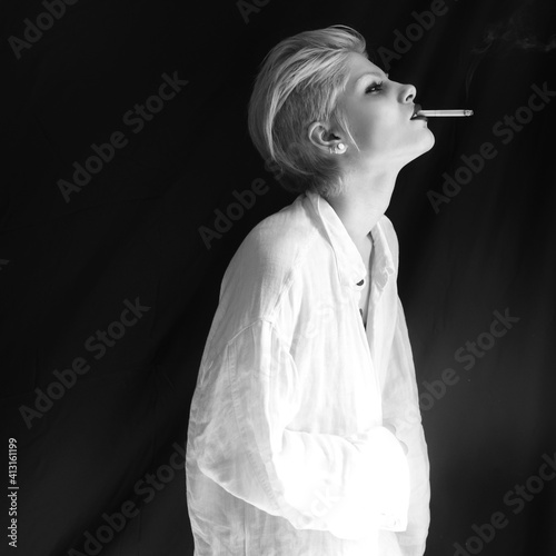 Mid Adult Woman Smoking Cigarette Looking Away While Standing Against Black Background