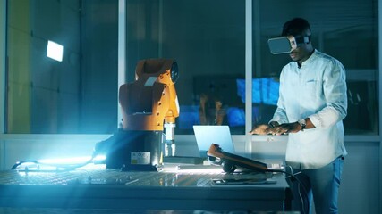 Wall Mural - african scientist in vr-glasses is operating a robotic arm