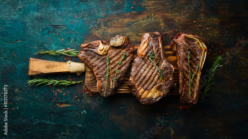 Grilled meat steaks on a wooden board: t-bone, striploin, Rib eye, new york steak. Top view. Rustic style. © Yaruniv-Studio