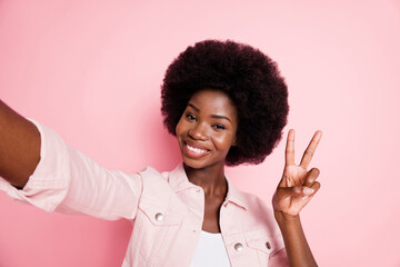 Poster - Self-portrait of cute lovely cheerful wavy-haired girl showing v-sign isolated over pink pastel color background