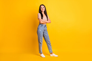 Sticker - Full size photo of young happy cheerful positive good mood smiling girl with crossed hands isolated on yellow color background