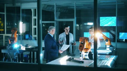 Wall Mural - team of scientists are discussing a robotic arm. professional engineers working at modern industrial