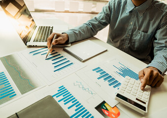 Businessmen are analyzing business graphs on their desks and calculating them using a calculator. Financial and accounting business concept.