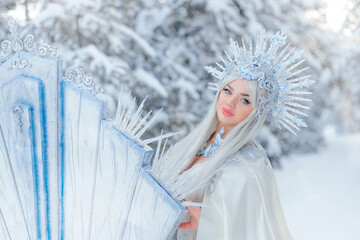 Young girl snow queen in the forest. The crown of the snow queen, the throne of ice. The queen's puffy dress. Diadem. Fabulous snowy forest. Fantasy concept