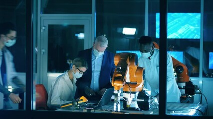 Wall Mural - scientists in face masks are observing robots in the lab