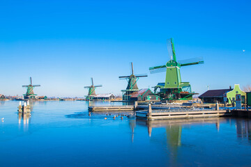 The Netherlands in winter. Winter Dutch village. Vintage beautiful Dutch houses, old windmills, frozen water in canals and rivers.