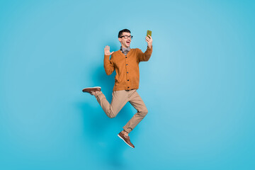 Sticker - Full length photo of young excited man jump up wave hello make selfie videocall cellphone isolated over blue color background