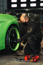 Mechanic Changing The Wheels Of A High-end Super Sports Car. Auto Mechanic Working In Garage. Repair Service.