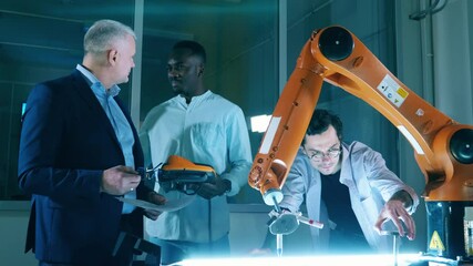 Wall Mural - male researchers are talking while operating a robotic arm. team of engineers working in modern inno