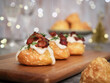 © Pkheawtasang - French savory choux dough cheese puff filled with traditional Béchamel sauce top with crispy fried bacon and dill leaf. Christmas decoration light festive bokeh and glass of Champagne in background