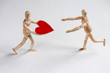 One Wooden Mannequin Holding A Heart And Running Towards Another