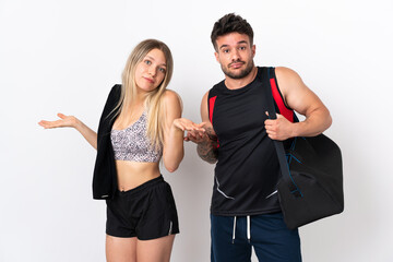 Poster - Young sport couple isolated on white background having doubts while raising hands and shoulders