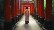 Japanese woman in a summer kimono walks under the Torii Gates.
