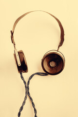 Old headphones with a long wire. Yellow toning vintage radio headphones on a light background. The concept of ancient radio engineering.