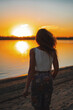 © Kseniia - Portrait of young woman as silhouette by the river sunset