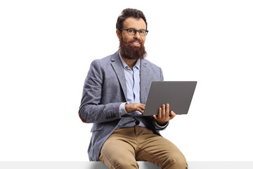 Wall Mural - Bearded man seated on a blank panel with a laptop