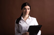 © Павел Костенко - Serious brunette business woman with folder in hands on brown background in studio