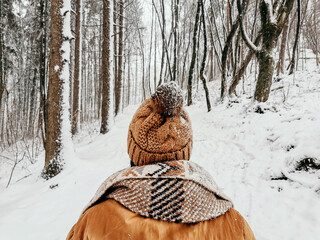 A young female in a brown pom-pom hat and ornamented scarfrest