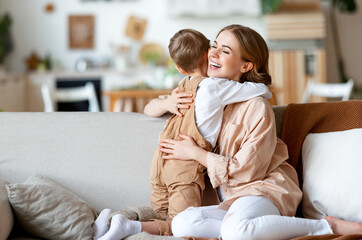 Wall Mural - happy mother hugging son on sofa