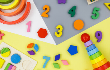 Wall Mural - Wooden kids toys on colourful paper. Educational toys blocks, pyramid, pencils, numbers . Toys for kindergarten, preschool or daycare. Copy space for text. Top view