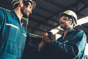 Two skillful factory engineer or worker showing teamwork and partnership . Industrial people and manufacturing labor concept .