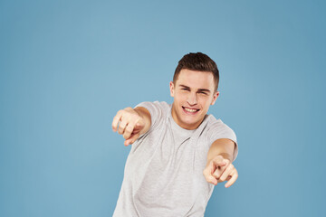 cheerful man in a white t-shirt gesturing with his hands emotions blue background