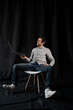 © Alexander - Pleasant positive business man using laptop.Happy smiling man in shirt works on laptop on a dark background