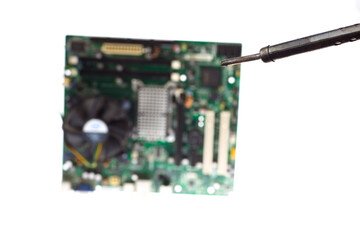 vintage soldering iron on the background of the computer motherboard located on a white background