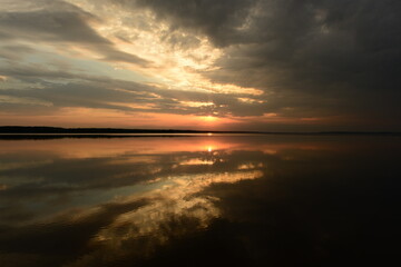 Wall Mural - majestic and beautiful sunset in the dark clouds of the sky above the calm water of the lake