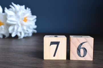 Wall Mural - Number 76, rating, award, Empty cover design in natural concept with a number cube and peony flower on wooden table for a background.