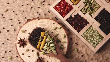 Wall Mural - Indian spices for Indian cooking Masala hot spicy curry  whole spices turmeric, cardamom, black pepper in wooden spoon 4K slow motion video footage  paprika in Indian spice box Kerala India Sri Lanka.