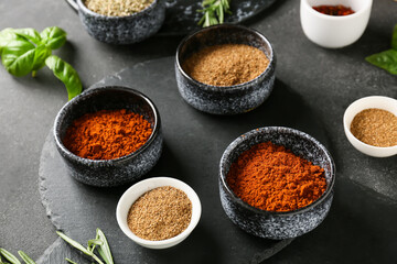 Bowls with different spices on dark background