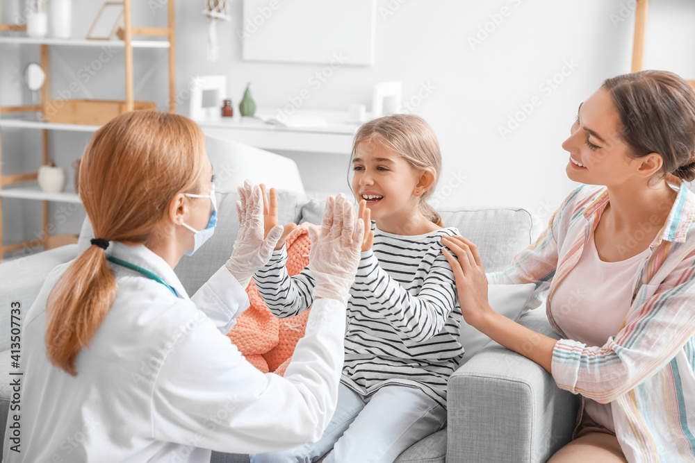 Pediatrician examining little girl at home
