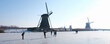 people skate on the ice near kinderdijk with al lot of windmills in holland on sunny winter day