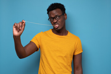 Wall Mural - Young african man pulling a chewing gum. Studio shot on blue wall.