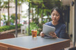 © syaheir - Portrait of a cheerful Asian woman while sitting in a coffee shop with a tablet in her hands