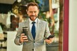 © Krakenimages.com - Middle age businessman using smartphone and drinking coffee at the city.