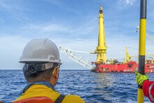 An Engineer Looking Away While Waiting To Be Disembarked From A Crew Boat Onto A Construction Vessel At Oil Field