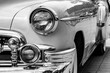 © Nataliya - Retro-styled front of a classic car with round headlights in black and white image. The headlights are finished in shiny chrome. The concept of a poster on the wall. horizontal image