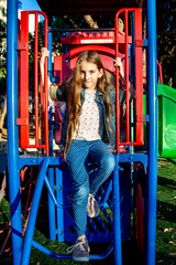 beautiful teenage girl with loose hair on the city children's playground on sunny day