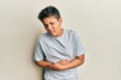 © Krakenimages.com - Teenager hispanic boy wearing casual grey t shirt with hand on stomach because indigestion, painful illness feeling unwell. ache concept.