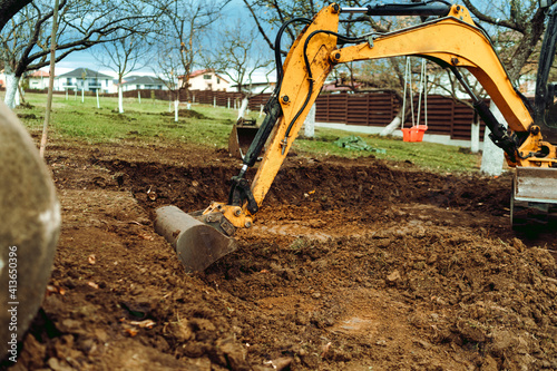 Obraz Dibond Landscaping works in the home garden at construction site with mini yellow excavator