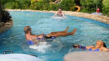 Tourists Enjoys Riding The Round Floaters In The Lazy River At A Waterpark.
