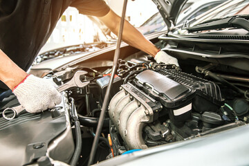 Close-up hands of auto mechanic are using the wrench to repair and maintenance auto engine is problems at car repair shop. Concepts of car care check and fixed and services insurance.