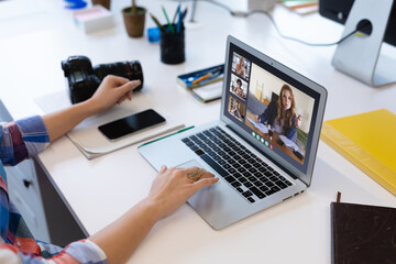 Sticker - Caucasian woman in office having video call with diverse colleagues displayed on laptop screen